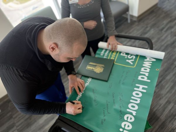 Patrick signing the DAISY Award banner